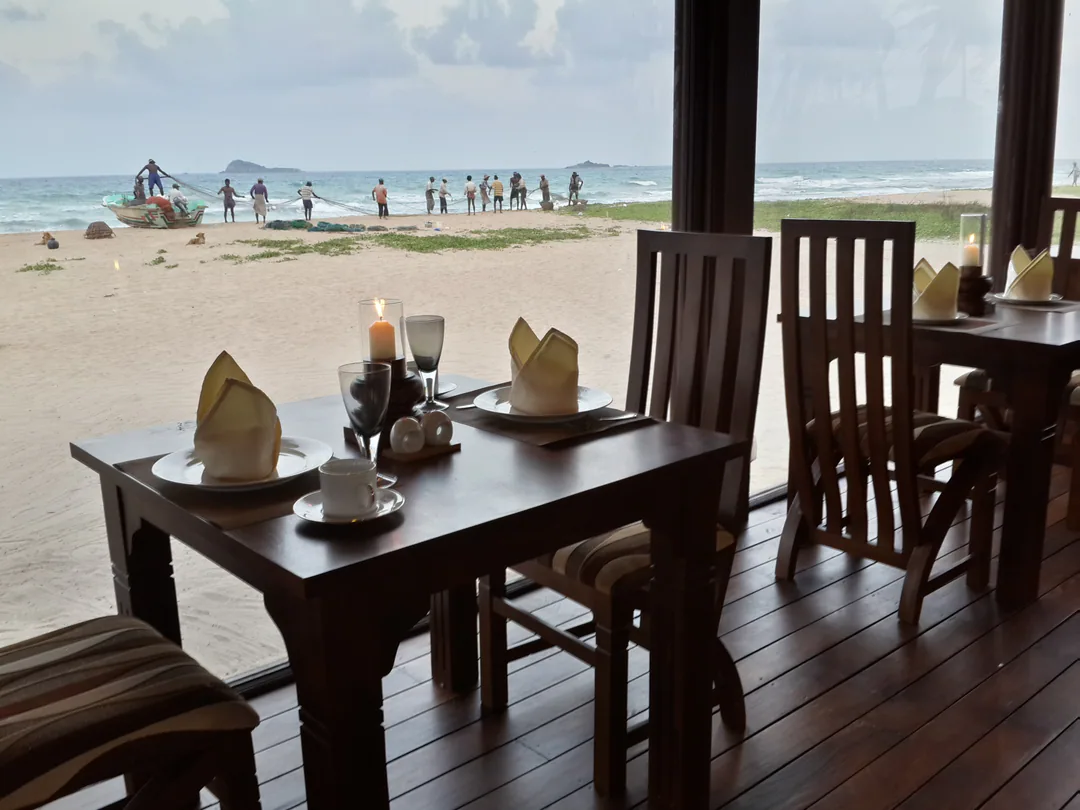 A candlelit table for two in the timber restaurant, looking out over the sand to fishermen hauling in their nets