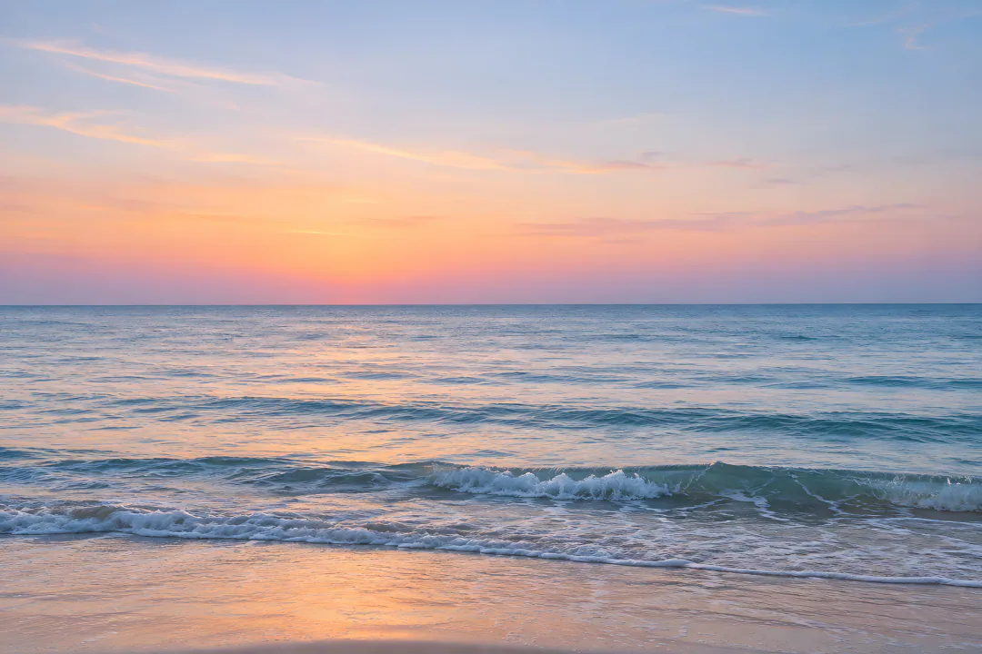 The sea at dawn, pink and gold over gentle waves