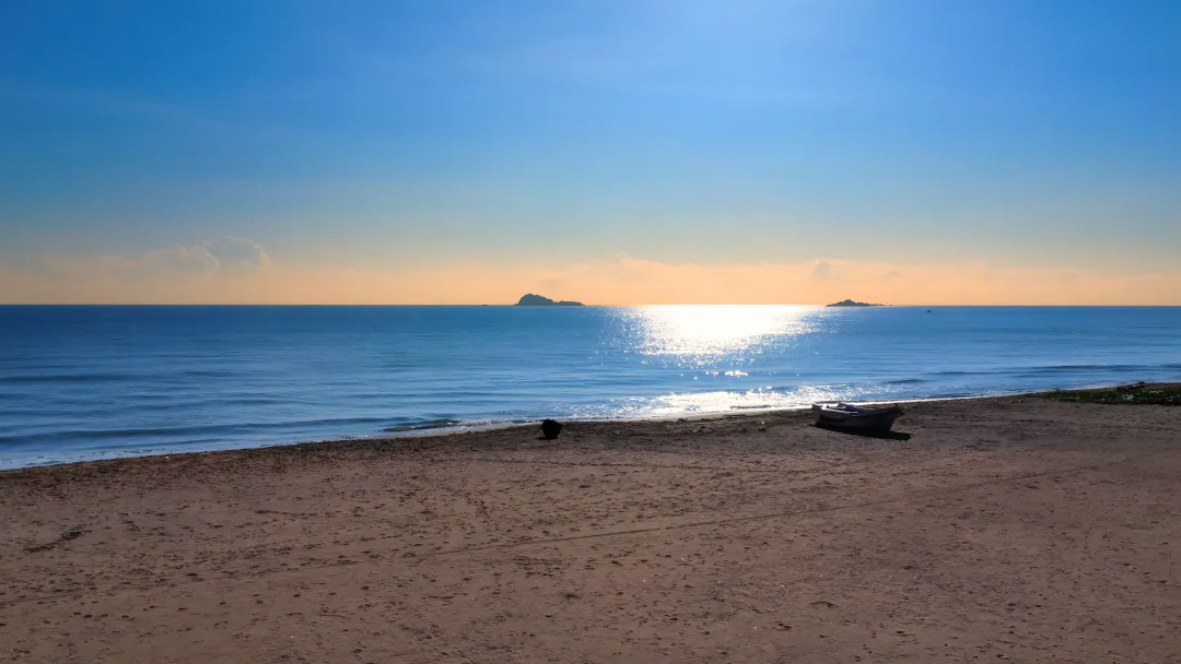 Morning light over the sea at Nilaveli, with a small boat resting on the sand