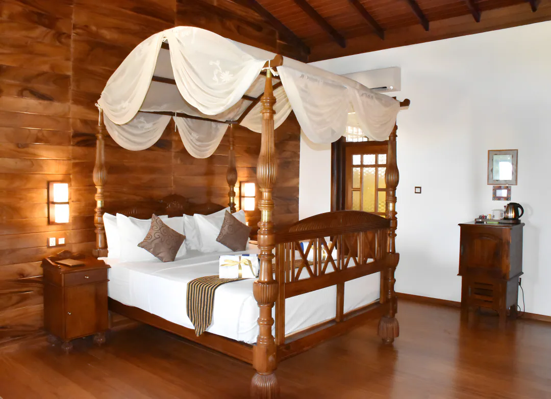 A room with a carved four-poster bed and white canopy