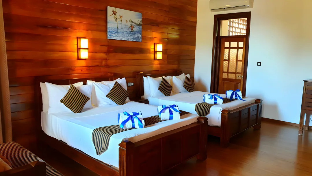 The Premium Quadruple room with two double beds, striped cushions and blue towel ribbons